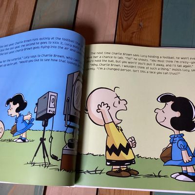 Sale Photo Thumbnail #259: Hardcover Peanuts picture book titled 'Kick the Football, Charlie Brown!' by Charles M. Schulz. Features full-color illustrations featuring Charlie Brown and Lucy. Clean interior pages with bright orange endpapers. Overall in good condition with minimal w