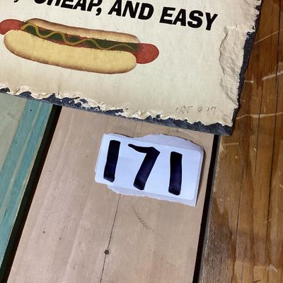 Sale Photo Thumbnail #265: A slate hanging wall plaque featuring the humorous phrase: "IF WE ARE WHAT WE EAT THEN I'M FAST, CHEAP, AND EASY" above a hot dog graphic. Signed/dated CNE '97 on the front lower corner. Features prepunched holes at the top for hanging and a rough deckled