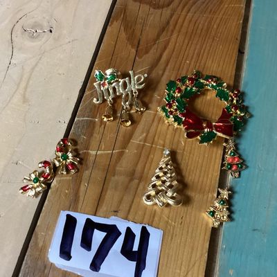 Sale Photo Thumbnail #276: Collection of festive Christmas-themed fashion jewelry, including:
- Enamel wreath brooch with red bow accent and dangling Christmas tree
- Gold-tone 'Jingle' pin with dangling bell charms
- Gold-tone woven Christmas tree brooch with rhinestone top
- Two 