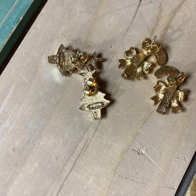 Sale Photo Thumbnail #281: Collection of festive Christmas-themed fashion jewelry, including:
- Enamel wreath brooch with red bow accent and dangling Christmas tree
- Gold-tone 'Jingle' pin with dangling bell charms
- Gold-tone woven Christmas tree brooch with rhinestone top
- Two 