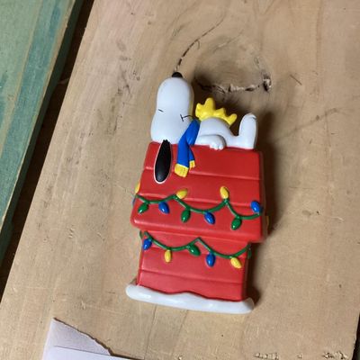 Sale Photo Thumbnail #290: Vintage Hallmark Cards Peanuts collectible lapel pin featuring Snoopy and Woodstock sleeping atop a red doghouse decorated with Christmas lights. Marked on back '© UFS HMK. CDS.' Pin clasp on back intact. Measures approximately 2 inches tall. In good pre