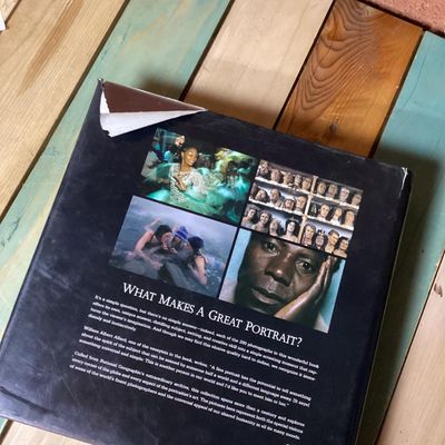 Sale Photo Thumbnail #308: Hardcover photography book titled 'In Focus: National Geographic Greatest Portraits'. Features 280 portrait photographs spanning over a century. Includes original dust jacket. Dust jacket shows some wear and a tear on the back corner, but internal pages r