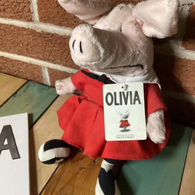 Sale Photo Thumbnail #310: Pairing of an 'Olivia' hardcover children's book by Ian Falconer alongside a matching 2001 Gund plush doll made exclusively for FAO Schwarz. Plush includes original hangtags and sewn-in tags. Both items are in good pre-owned condition with light wear.