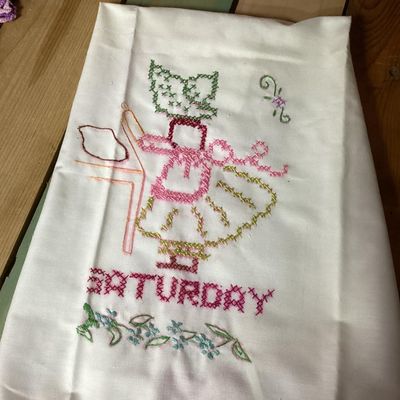 Sale Photo Thumbnail #323: Set of vintage white cotton kitchen/tea towels featuring cross-stitched embroidered designs for days of the week (Sunday through Saturday). Each towel depicts a Sunbonnet Sue/chores motif with colorful crocheted lace trim at the bottom hem. Appears to be 