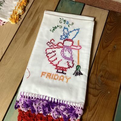 Sale Photo Thumbnail #322: Set of vintage white cotton kitchen/tea towels featuring cross-stitched embroidered designs for days of the week (Sunday through Saturday). Each towel depicts a Sunbonnet Sue/chores motif with colorful crocheted lace trim at the bottom hem. Appears to be 
