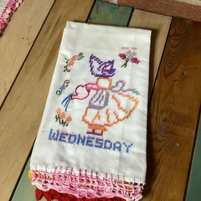 Sale Photo Thumbnail #320: Set of vintage white cotton kitchen/tea towels featuring cross-stitched embroidered designs for days of the week (Sunday through Saturday). Each towel depicts a Sunbonnet Sue/chores motif with colorful crocheted lace trim at the bottom hem. Appears to be 
