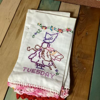 Sale Photo Thumbnail #319: Set of vintage white cotton kitchen/tea towels featuring cross-stitched embroidered designs for days of the week (Sunday through Saturday). Each towel depicts a Sunbonnet Sue/chores motif with colorful crocheted lace trim at the bottom hem. Appears to be 