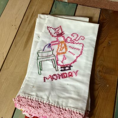 Sale Photo Thumbnail #318: Set of vintage white cotton kitchen/tea towels featuring cross-stitched embroidered designs for days of the week (Sunday through Saturday). Each towel depicts a Sunbonnet Sue/chores motif with colorful crocheted lace trim at the bottom hem. Appears to be 