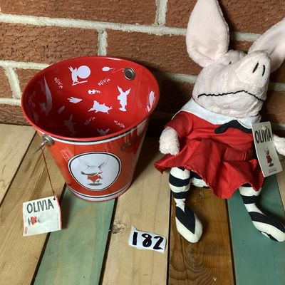 Sale Photo Thumbnail #324: Collection of vintage Olivia the Pig items featuring a GUND plush doll wearing a red dress with original tags attached and a matching Schylling red tin pail with handle and original tag attached (dated 2003). Both items are in good overall condition with 