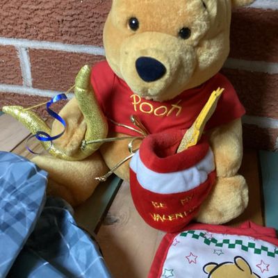 Sale Photo Thumbnail #357: Lot of Disney Winnie the Pooh collectibles including a Cupid Valentine plush with wings, a honey pot, bow and arrow; a blue plaid umbrella with Pooh graphic and honey pot handle; and a quilted Christmas themed pot holder. Items show light wear consistent 