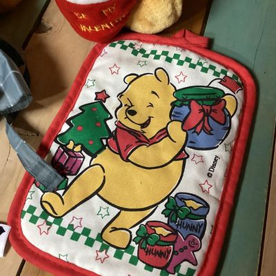 Sale Photo Thumbnail #358: Lot of Disney Winnie the Pooh collectibles including a Cupid Valentine plush with wings, a honey pot, bow and arrow; a blue plaid umbrella with Pooh graphic and honey pot handle; and a quilted Christmas themed pot holder. Items show light wear consistent 