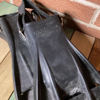 Sale Photo Thumbnail #365: Pair of vintage black rubber swim/scuba fins marked 'WATERLUNG 707' and size 'LARGE'. Features open heel with adjustable heel straps and metal buckles. Fins show signs of age and wear including surface marks and scuffs consistent with light use. Rubber re