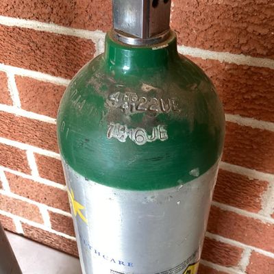Sale Photo Thumbnail #369: A set of three aluminum compressed oxygen tanks labeled for medical/U.S.P. use, featuring CGA 870 post valves. Includes markings from Apria Healthcare and Sherwood valves. Shows typical surface scuffs, wear, and sticker residue from prior use and transpor