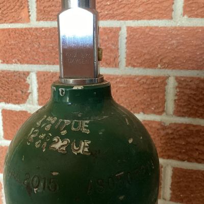 Sale Photo Thumbnail #371: A set of three aluminum compressed oxygen tanks labeled for medical/U.S.P. use, featuring CGA 870 post valves. Includes markings from Apria Healthcare and Sherwood valves. Shows typical surface scuffs, wear, and sticker residue from prior use and transpor