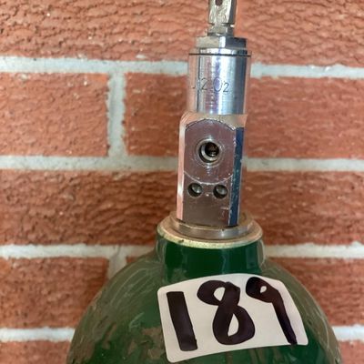 Sale Photo Thumbnail #374: Set of three medical compressed oxygen cylinders with Sherwood valves and Apria Healthcare labels. Aluminum bodies with green tops. Used condition with visible surface scratches, scuffs, and sticker residue. Hydrotest dates and specifications stamped on c