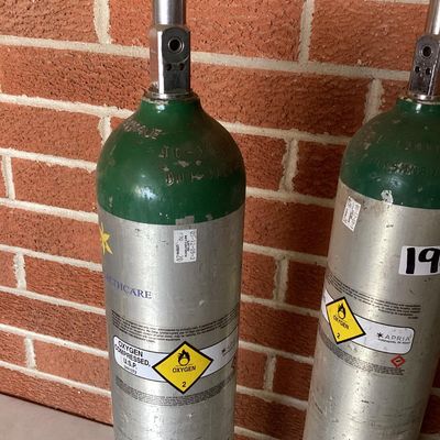 Sale Photo Thumbnail #375: Set of three medical compressed oxygen cylinders with Sherwood valves and Apria Healthcare labels. Aluminum bodies with green tops. Used condition with visible surface scratches, scuffs, and sticker residue. Hydrotest dates and specifications stamped on c