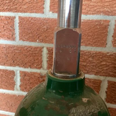 Sale Photo Thumbnail #373: Set of three medical compressed oxygen cylinders with Sherwood valves and Apria Healthcare labels. Aluminum bodies with green tops. Used condition with visible surface scratches, scuffs, and sticker residue. Hydrotest dates and specifications stamped on c