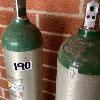 Sale Photo Thumbnail #376: Set of three medical compressed oxygen cylinders with Sherwood valves and Apria Healthcare labels. Aluminum bodies with green tops. Used condition with visible surface scratches, scuffs, and sticker residue. Hydrotest dates and specifications stamped on c