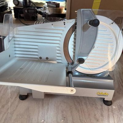 Sale Photo Thumbnail #164: Cabela's / Chef'sChoice electric food slicer with large serrated stainless steel blade, blade guard, tilted food carriage with food pusher/guard, adjustable thickness control, and non-skid feet. Ideal for deli meats, venison, jerky, cheese, and bread.
Con