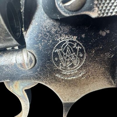Sale Photo Thumbnail #11: This revolver has the no-dash serial number, meaning that it was issued prior to any significant mechanical changes made later by Smith & Wesson. It has the original diamond checkered wood grips. The barrel measures two inches long. This revolver shows so