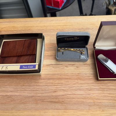 Sale Photo Thumbnail #38: Group of 3 boxed men's accessories featuring a brown Rolfs Two-Fold leather wallet in original box, a gold-tone Christian Dior tie clasp/bar in a original velvet lined box, and a silver-tone pocket knife in a padded presentation box. All items appear in g
