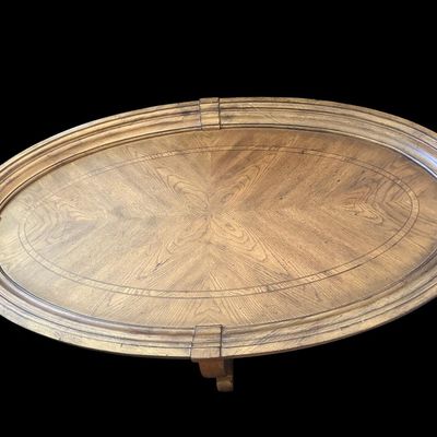 Sale Photo Thumbnail #168: 52"L × 30"W × 18"T. Hidden casters. Beautiful oval coffee table featuring starburst oak veneer wood inlay top  molded picture-frame gallery edge  cabriole legs  and lower oval wood display shelf. Hidden casters mounted on underside for easy moving. Dime