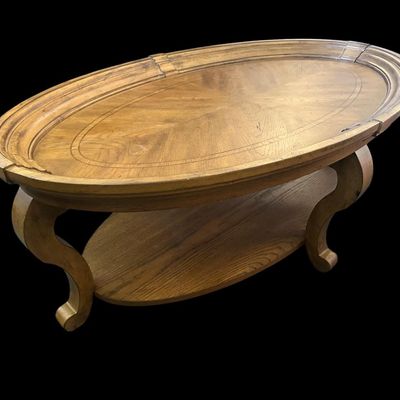 Sale Photo Thumbnail #169: 52"L × 30"W × 18"T. Hidden casters. Beautiful oval coffee table featuring starburst oak veneer wood inlay top  molded picture-frame gallery edge  cabriole legs  and lower oval wood display shelf. Hidden casters mounted on underside for easy moving. Dime