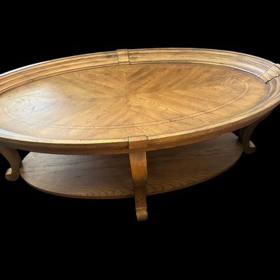 Sale Photo Thumbnail #166: 52"L × 30"W × 18"T. Hidden casters. Beautiful oval coffee table featuring starburst oak veneer wood inlay top  molded picture-frame gallery edge  cabriole legs  and lower oval wood display shelf. Hidden casters mounted on underside for easy moving. Dime