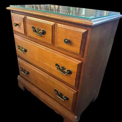 Sale Photo Thumbnail #228: 26"T × 24"W × 15"D Solid wood nightstand/chest featuring glass top cover  3 storage drawers with brass bail pulls  and bracket feet. Dimensions: 26" Tall x 24" Wide x 15" Deep.  