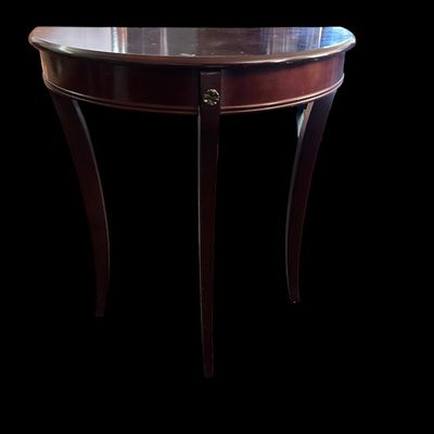 Sale Photo Thumbnail #257: 29"T × 24"W × 12"D Half-moon demilune accent table in rich mahogany finish featuring smooth curved apron  central floral brass medallion detail  and three slender splayed cabriole-style legs. Dimensions: 29" Tall x 24" Wide x 12" Deep.  