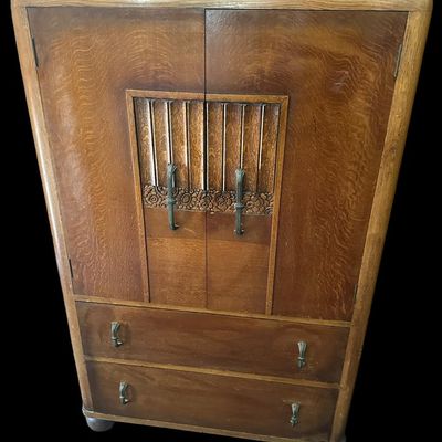 Sale Photo Thumbnail #469: 48"T × 29"W × 18"D Oak cabinet with two upper doors (carved center panel with vertical slats and floral detail)  two lower drawers  and bun feet. Interior has a shelf. Measurements: 48" tall × 29" wide × 18" deep. Local  .  