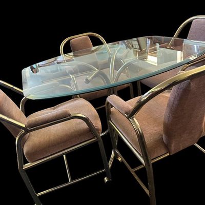 Sale Photo Thumbnail #671: 48"L × 42"W × 28.5"T. Set of 4 chairs. Vintage 5-piece casual dining/game set featuring a rounded glass top table on tubular brass legs  paired with 4 matching brass frame armchairs with mauve/taupe fabric upholstery on rolling caster wheels. 48"L × 42