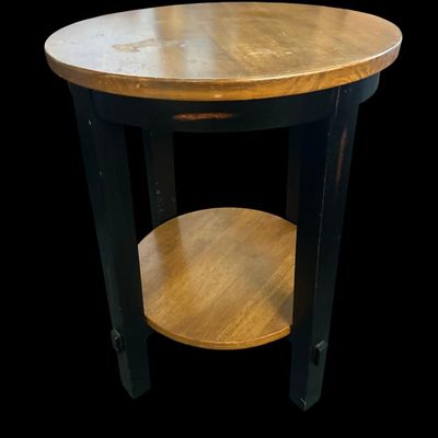 Sale Photo Thumbnail #739: 26.00 Tall 19.50 Round Round wood end table with a warm natural wood grain top and lower shelf paired with distressed black square legs. 26.00 Tall 19.50 Round  