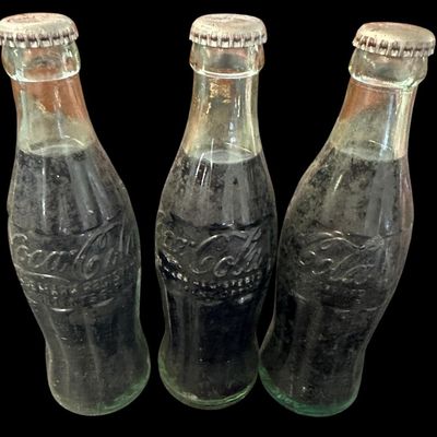 Sale Photo Thumbnail #864:  Three capped / still-full 6.5 oz Coca-Cola bottles. Two Monroe  one Shreveport. Do not wash. Collectible  not for drinking.