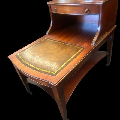 Sale Photo Thumbnail #969: 24.00 x 19.00 x 26.00 Classic 2-tier step-down end table featuring gold-tooled leather inlays on both upper and lower surface tiers  top drawer with brass ring pulls  and lower curved open shelf base.  