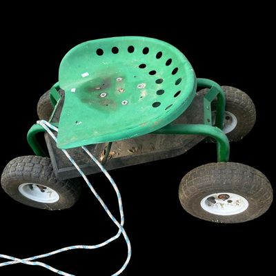 Sale Photo Thumbnail #988: Mobile rolling garden work stool featuring a green metal tractor-style swivel seat  under-seat tool tray  pneumatic tires  and front pull rope.  