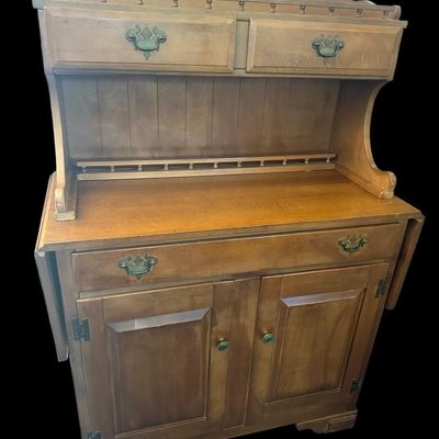 Sale Photo Thumbnail #1075: 53"T × 18"D × 38"W (down) / 62"W (up) Upper hutch with spindle gallery top rail and dual small drawers; main cabinet features drop-leaf sides  single wide drawer over double cabinet doors  and antique brass batwing bail handles. Dimensions: 53" H x 18" 
