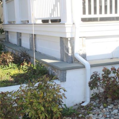 Sale Photo Thumbnail #191: Exterior view of a residential porch featuring white railings, stone pillar accents, and surrounding landscaping.