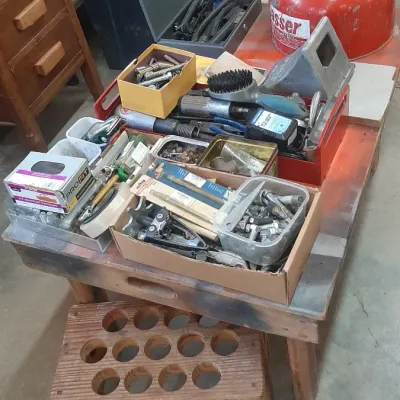 Assorted workshop tools, hardware, and supplies, including a vintage red gas can, metal toolboxes, and organized containers set atop a...
