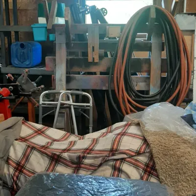 Workshop storage area featuring heavy-duty coiled hoses, plastic shelving, a folding walker, and various household supplies.