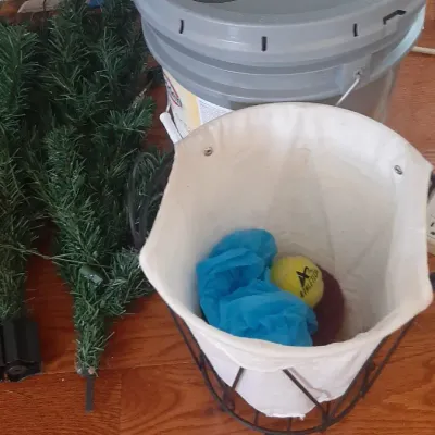 Collection of household items including artificial Christmas tree sections, a large grey sealed bucket, and a wire mesh laundry hamper...