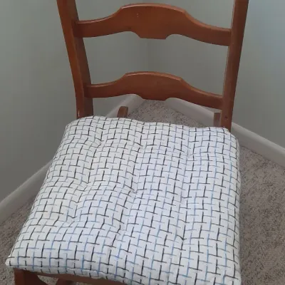 Vintage wooden ladder-back rocking chair featuring a warm stain finish and a removable patterned seat cushion.