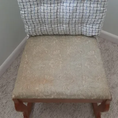 Wooden rocking chair featuring a beige floral upholstered seat and a blue and white patterned tufted back cushion.