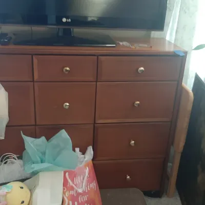 Large wooden dresser featuring eleven drawers with brass brass knobs, topped by a flat-screen television.