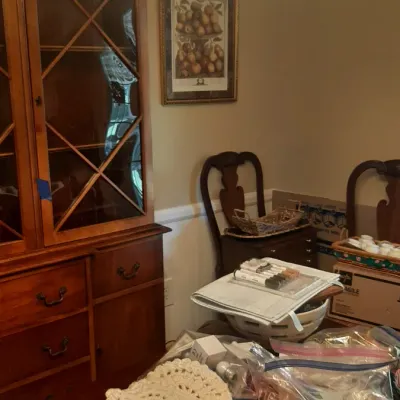 Traditional wooden china cabinet with glass display doors, accompanied by a dining room set and various household craft items.