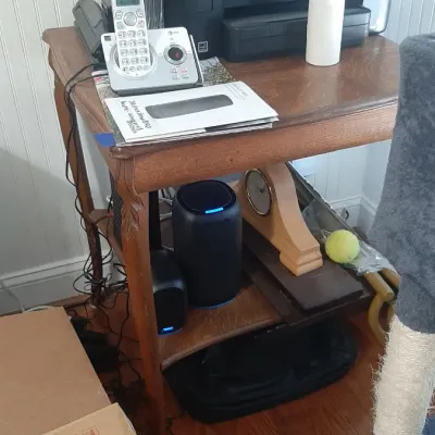 A wooden two-tier side table holding home office electronics, including a black Epson printer, AT&T cordless telephone, and modern...