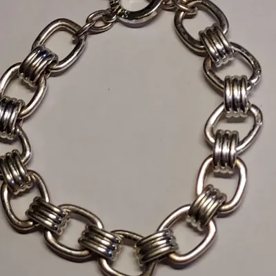 Sale Photo Thumbnail #227: This Chaps bracelet features a sleek and stylish link chain design with a toggle closure. The bracelet is made of metal material with a silvertone finish, and is signed by the brand. With a length of 7.7 inches, this bracelet is suitable for any occasion 