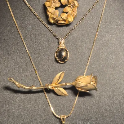 Sale Photo Thumbnail #257: Vintage Gold tone Set ~ 2 Necklaces & 2 Fashion Brooches
> necklace marked STC Karis w/ black n gold flake stone
> necklace with elongated pendant is 18" long w/lobster clasp
> 2 brooches .....pin perfect 
all in Vg condition