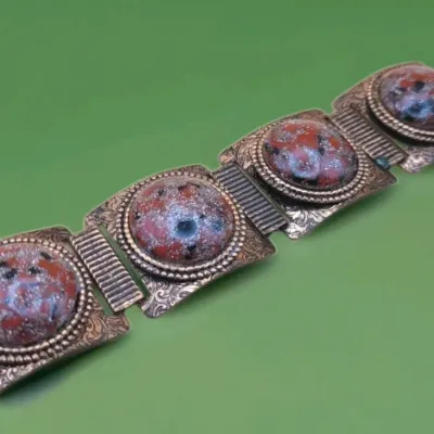 Sale Photo Thumbnail #272: This Vintage Natural Patina Copper & Red Confetti Lucite Cabochon Panel Bracelet features a unique design with simulated red cabochon stones set in copper. Measuring 7 inches in length,
excellent condition, cleaned and toned to luster