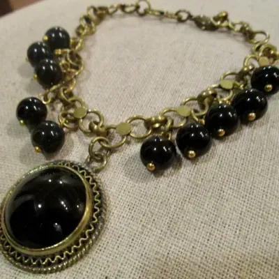 Sale Photo Thumbnail #128: Vintage dangling large Black Cabochon glass stone and dangling black beads on a 8" brass-tone chain bracelet.
> Monet marked 15" glass bead necklace w/ lobster clasp
> pair of stuff earring to coordinate